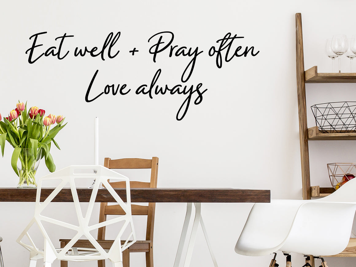 Wall decals for kitchen that say ‘Eat Well Pray Often Love Always’ in a script font on a kitchen wall.