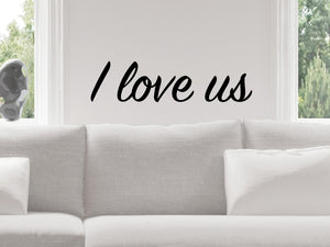Living room wall decals that say ‘I Love Us’ in a script font on a living room wall. 