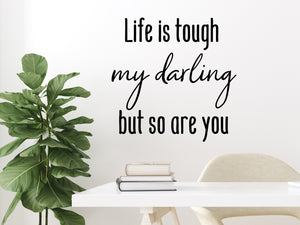 Wall decal for the office that says ‘Life Is Tough My Darling But So Are You’ in a script font on an office wall.