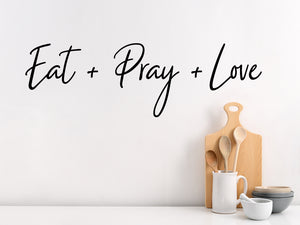 Wall decals for kitchen that say ‘Eat Pray Love’ in a script font on a kitchen wall.