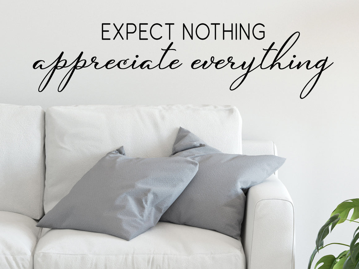 Living room wall decals that say ‘expect nothing appreciate everything’ on a living room wall. 