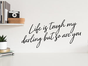Wall decal for the office that says ‘Life Is Tough My Darling But So Are You’ in a cursive font on an office wall.