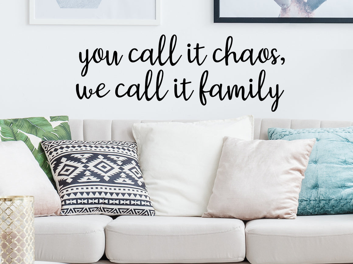 Living room wall decals that say ‘you call it chaos, we call it family’ in script font on a living room wall. 