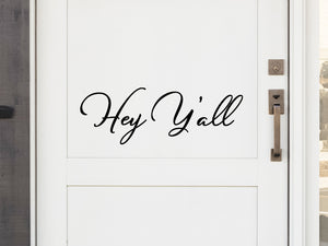 Front door decal that says, ‘Hey Ya’ll’ in a script font on a front porch door. 