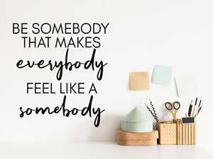 Wall decal for the office that says ‘Be Somebody That Makes Everybody Feel Like A Somebody’ in a bold font on an office wall.
