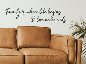 Living room wall decals that say ‘Family Is Where Life Begins And Love Never Ends’ in a cursive font on a living room wall. 
