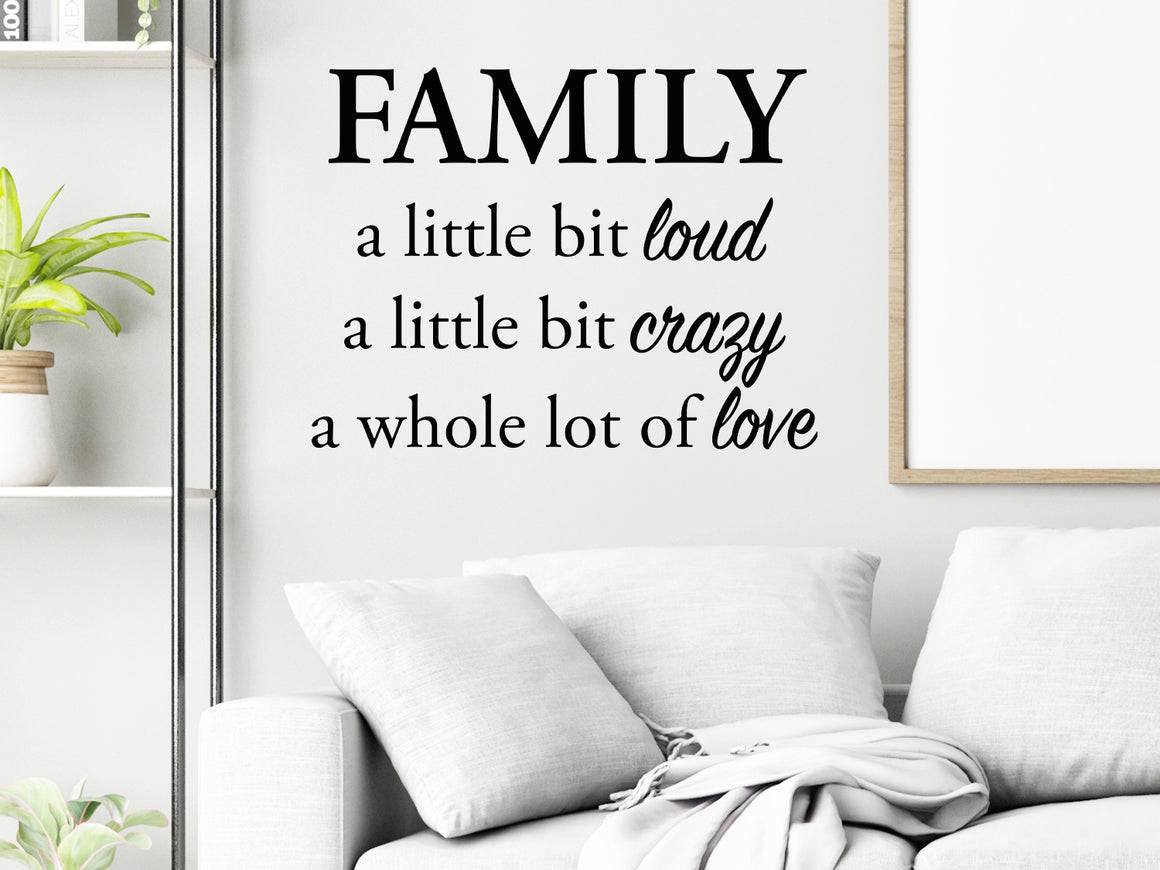 Living room wall decals that say ‘Family A Little Bit Loud A Little Bit Crazy & A Whole Lot Of Love’ in a script font on a living room wall.