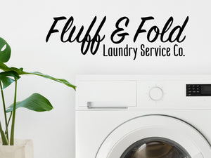 Laundry room wall decal that says ‘Fluff And Fold Laundry Service Co. Script’ on a laundry room wall.