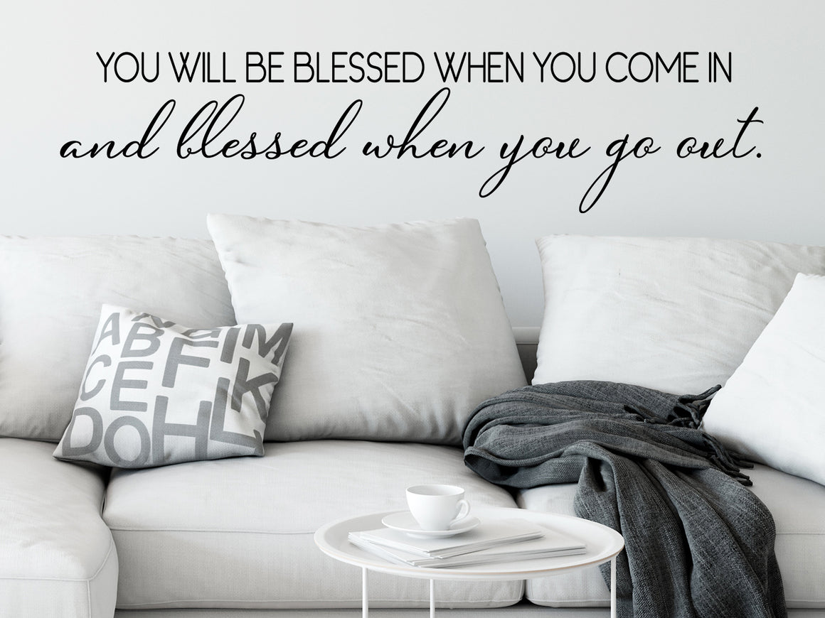 Living room wall decals that say ‘you will be blessed when you come in and blessed when you go out’ on a living room wall. 