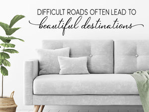 Living room wall decals that say ‘difficult roads often lead to beautiful destinations’ on a living room wall. 