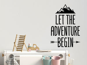 Wall decal for kids that says ‘Let The Adventure Begin’ with an arrow on a kid’s room wall. 