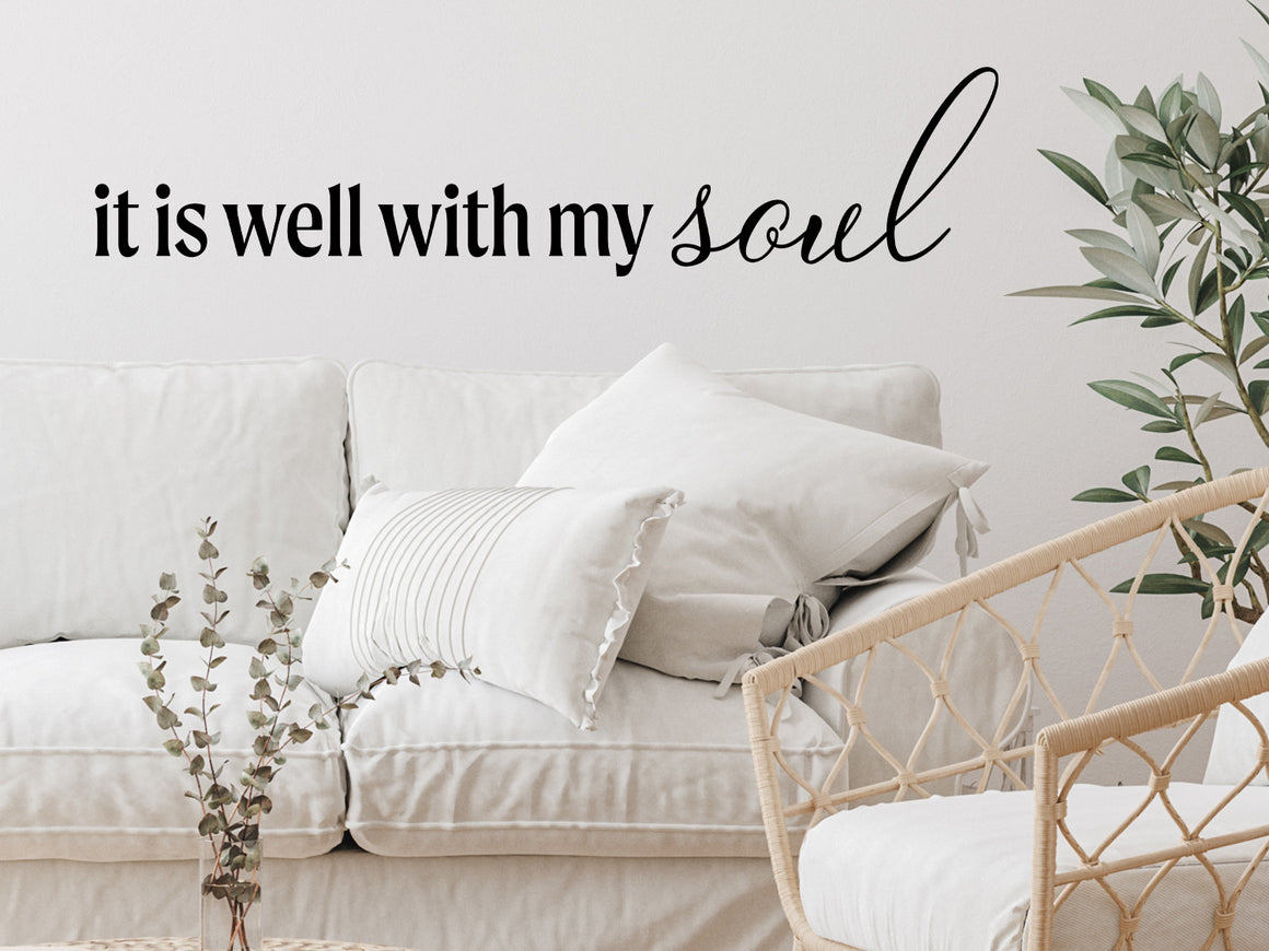 Living room wall decals that say ‘It Is Well With My Soul’ in a script font on a living room wall. 