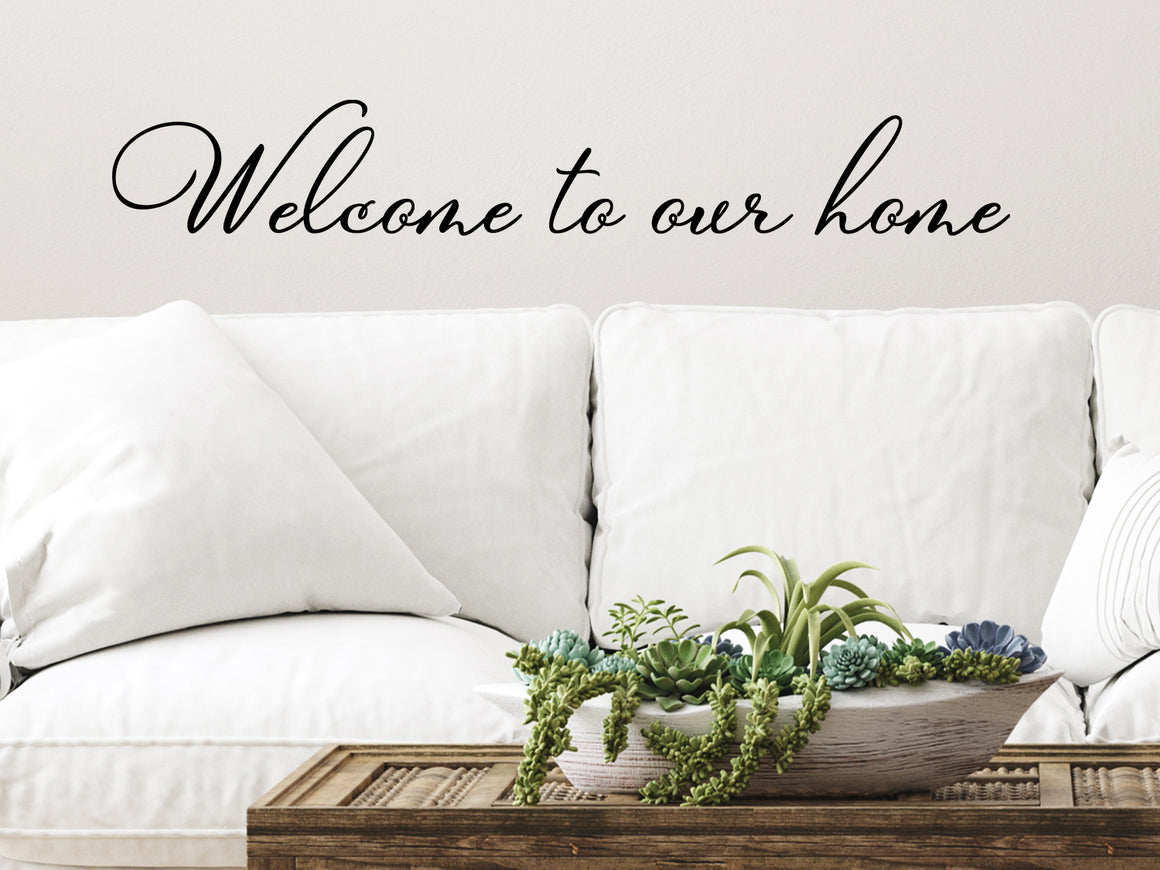 Living room wall decals that say ‘Welcome To Our Home’ in a cursive font on a living room wall. 