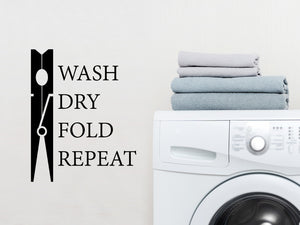 Laundry room wall decal that says ‘Wash Dry Fold Repeat' (ClothesPin) set Vertically on a laundry room wall.