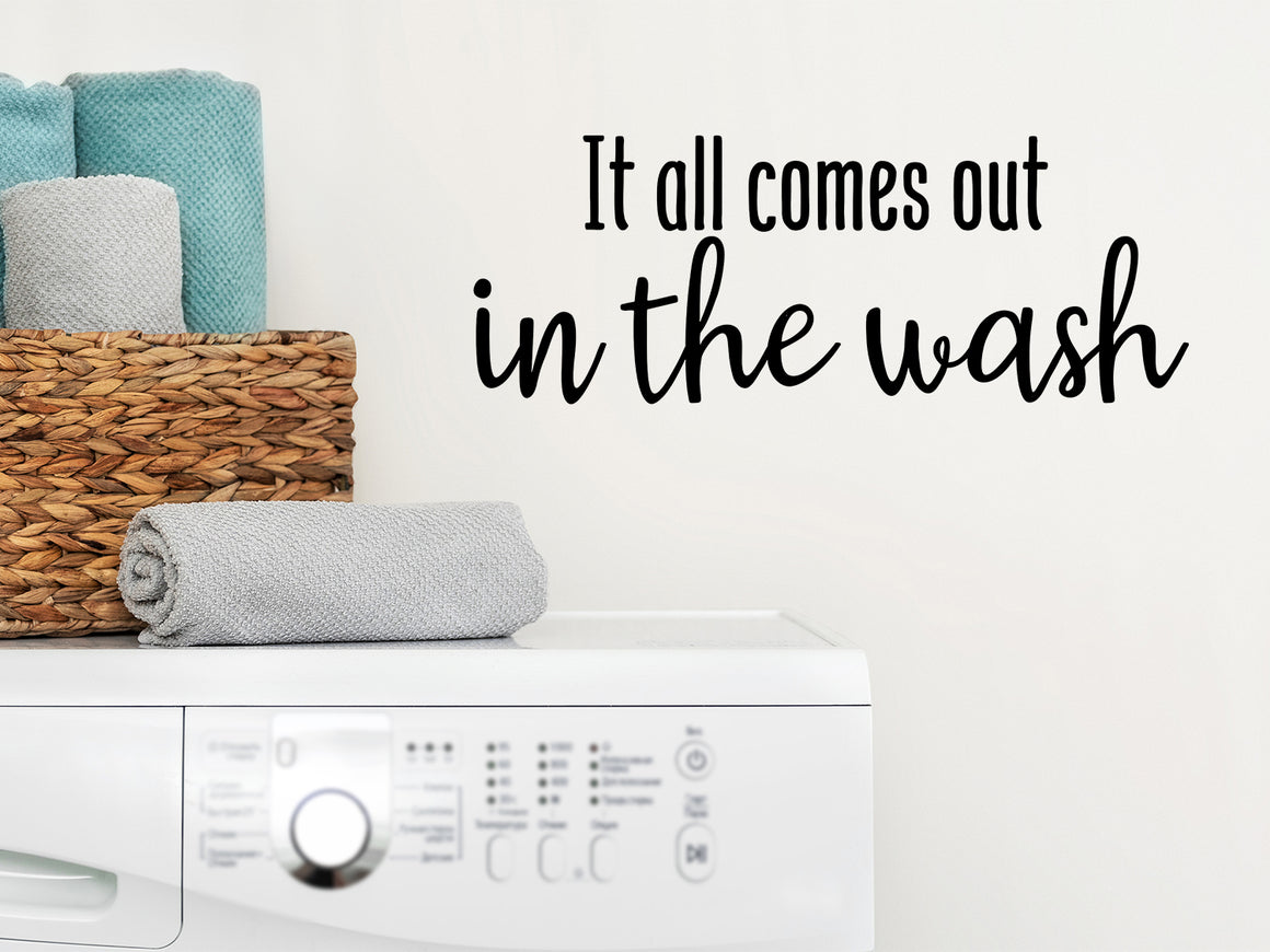 Laundry room wall decal that says ‘It All Comes Out In The Wash’ in a cursive font on a laundry room wall.
