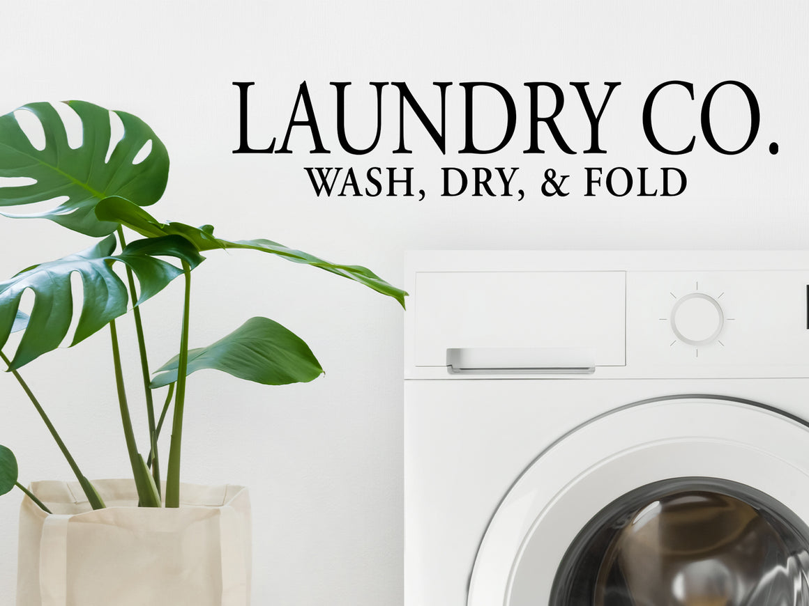 Laundry room wall decal that says ‘Laundry Co. sash, dry, & fold’ on a laundry room wall.