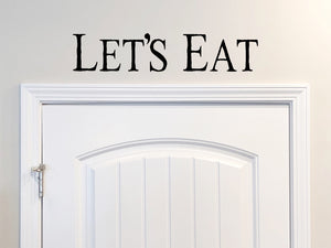 Wall decals for kitchen that say ‘Let's eat’ in a print font on a kitchen wall.