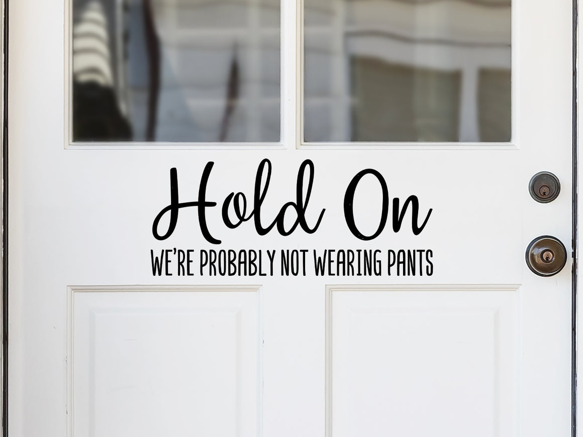 Front door decal that says, ‘Hold On We're Probably Not Wearing Pants Script’ on a front porch door. 