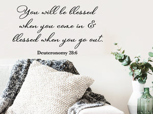 Living room wall decals that say ‘you will be blessed when you come & blessed when you go out’ on a living room wall. 