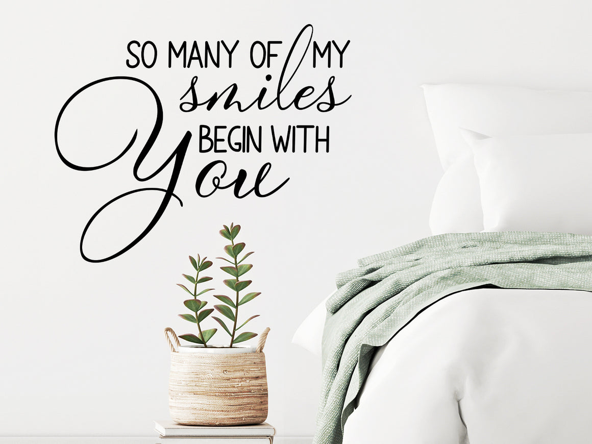 Wall decal for bedroom that says ‘so many of my smiles begin with you’ on a bedroom wall.