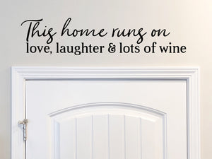 Wall decals for kitchen that say ‘This House Runs On Love Laughter And Lots Of Wine’ in a script font on a kitchen wall.