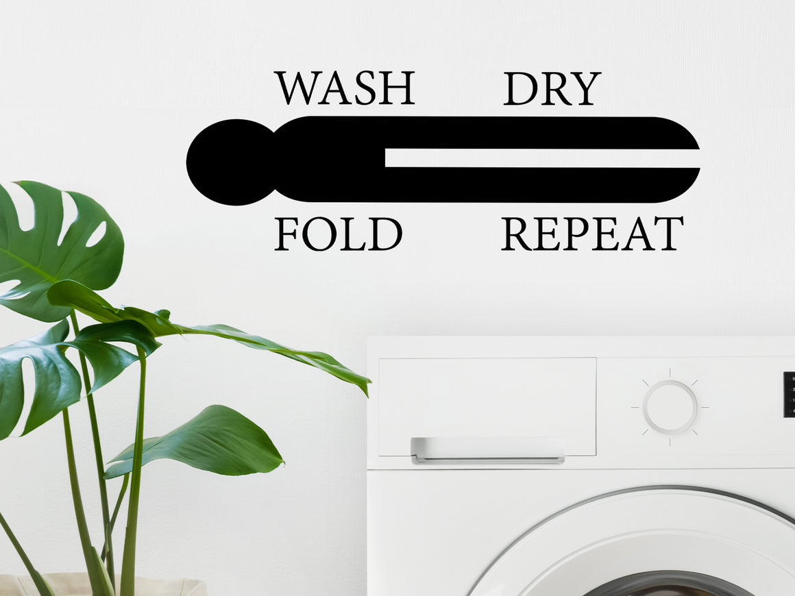 Laundry room wall decal that says ‘Wash Dry Fold Repeat (ClothesPin)’ in a print font on a laundry room wall.