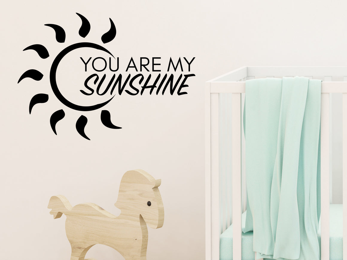 Wall decal for kids in a black color that says ‘You Are My Sunshine’ with a sun design on a kid’s room wall. 