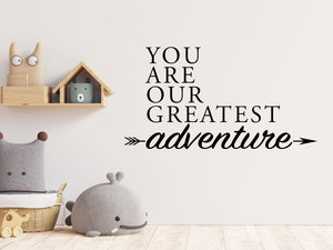 Wall decal for kids in a black color that says ‘You Are Our Greatest Adventure’ with an arrow design on a kid’s room wall. 