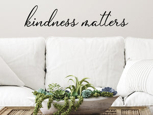 Living room wall decals that say ‘Kindness Matters’ in a cursive font on a living room wall. 