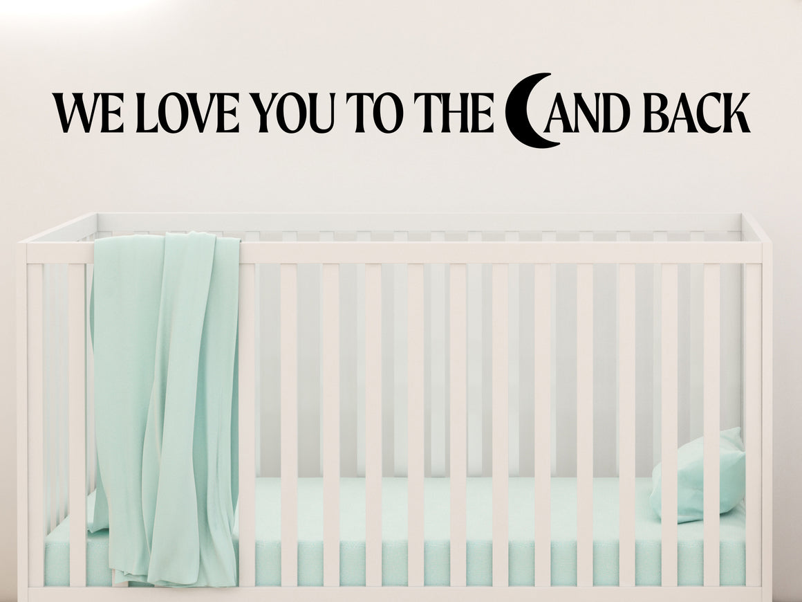 Wall decal for kids in a black color that says ‘We Love You To The Moon And Back’ in a bold font on a kid’s room wall. 