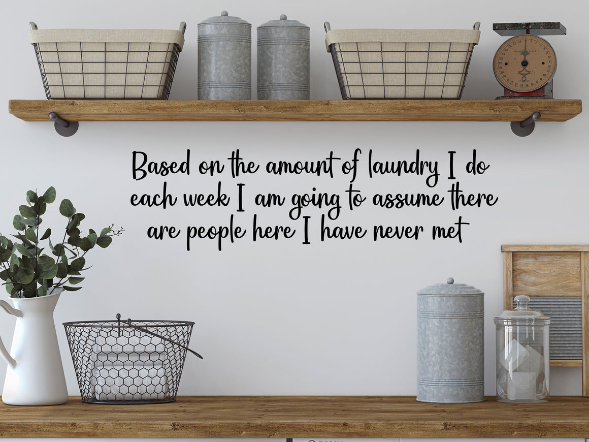Laundry room wall decal that says ‘Based On The Amount Of Laundry I Do Each Week I Am Going To Assume there are people here I have never met’ in a cursive font on a laundry room wall