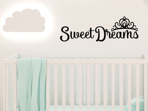 Wall decal for kids in a black color that says ‘Sweet Dreams’ in a cursive font on a kid’s room wall. 