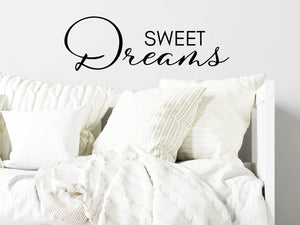 Wall decal for kids in a black color that says ‘Sweet Dreams’ in a script font on a kid’s room wall. 