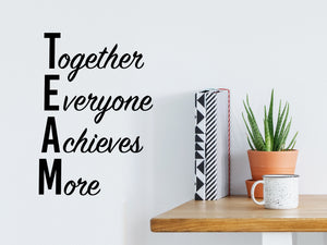 Wall decal for the office that says ‘TEAM Together Everyone Achieves More’ in a script font on an office wall.