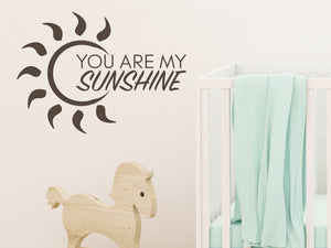 Wall decal for kids in a brown color that says ‘You Are My Sunshine’ with a sun design on a kid’s room wall. 