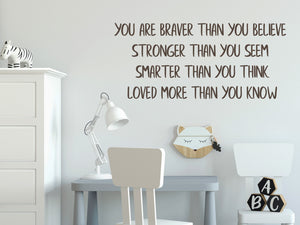 Wall decal for kids in a brown color that says ‘You Are Braver Than You Believe’ in a print font on a kid’s room wall. 