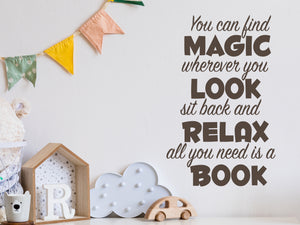 Wall decal for kids in a brown color that says ‘You Can Find Magic Wherever You Look’ in a dual font on a kid’s room wall. 