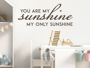 Wall decal for kids in a brown color that says ‘You Are My Sunshine’ in a script font on a kid’s room wall. 