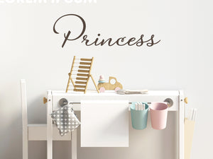 Wall decal for kids that says ‘Princess’ in brown in a cursive font on a kid’s room wall. 