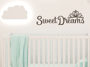 Wall decal for kids in a brown color that says ‘Sweet Dreams’ in a cursive font on a kid’s room wall. 