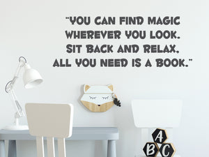 Wall decal for kids in a grey color that says ‘You Can Find Magic Wherever You Look’ in a bold font on a kid’s room wall. 
