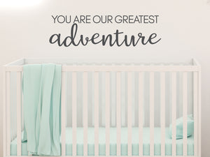 Wall decal for kids in a grey color that says ‘You Are Our Greatest Adventure’ in a script font on a kid’s room wall. 