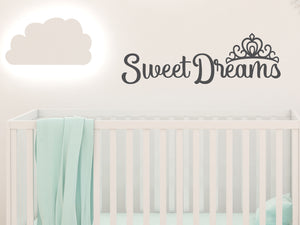 Wall decal for kids in a grey color that says ‘Sweet Dreams’ in a cursive font on a kid’s room wall. 