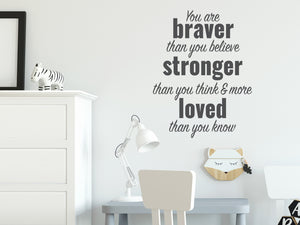 Wall decal for kids in a grey color that says ‘You Are Braver Than You Believe’ in a dual font on a kid’s room wall. 