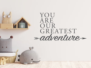Wall decal for kids in a grey color that says ‘You Are Our Greatest Adventure’ with an arrow design on a kid’s room wall. 