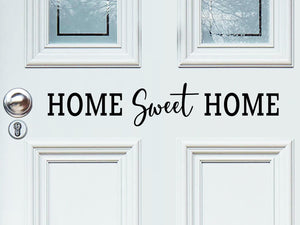 Front door decal that says, ‘home sweet home’ with a script font on a front porch door. 