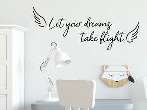 Wall decal for kids that says ‘Let Your Dreams Take Flight’ in a cursive font on a kid’s room wall. 