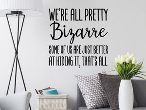Living room wall decals that say ‘We're all pretty bizarre some of us are just better at hiding it, that's all’ on a living room wall. 