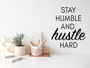 Wall decal for the office that says ‘Stay Humble And Hustle Hard’ in a script font on an office wall.