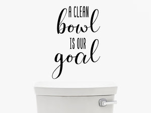 Wall decal for the bathroom that says ‘A clean bowl is our goal’ on a bathroom wall.
